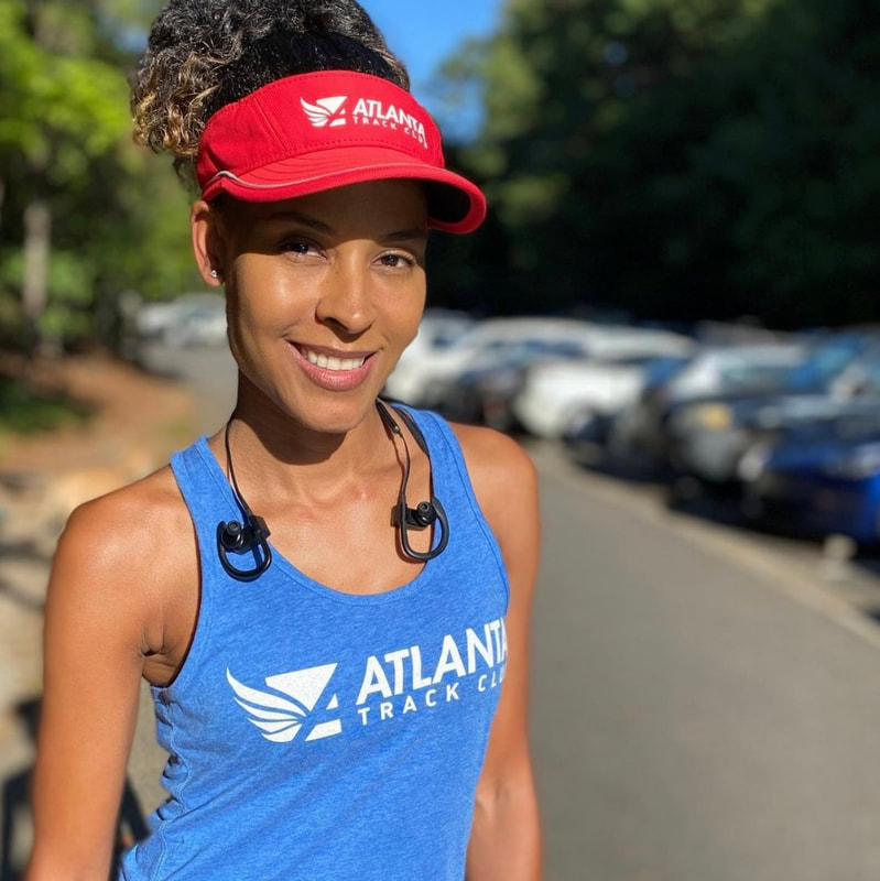 Woman runner wearing Atlanta Track Club visor and tank top on the running trail. 